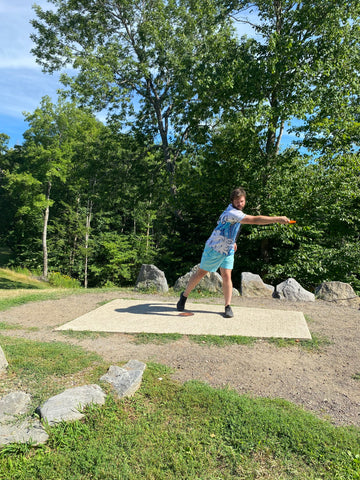 Andrew Streeter continues to demonstrate the disc golf X-Step drive with step 5 where he begins to pull the disc to its full length behind him.