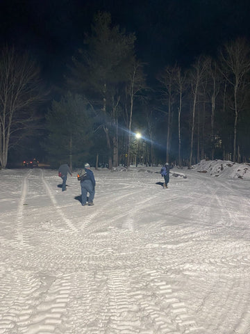 Cardmates making putts in the cold snow uner the lights at night disc golf at sabattus disc golf on their 9 hole owl course.